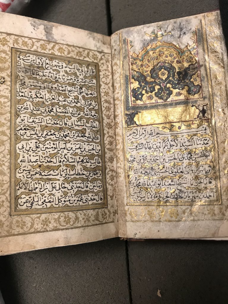 An open two page spread of an Arabic manuscript with gold leaf decorations