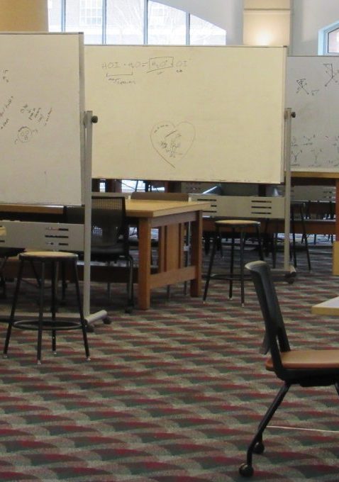 First floor study area at Grainger Engineering library with tables, chairs and whiteboards. The room has carpeted floor