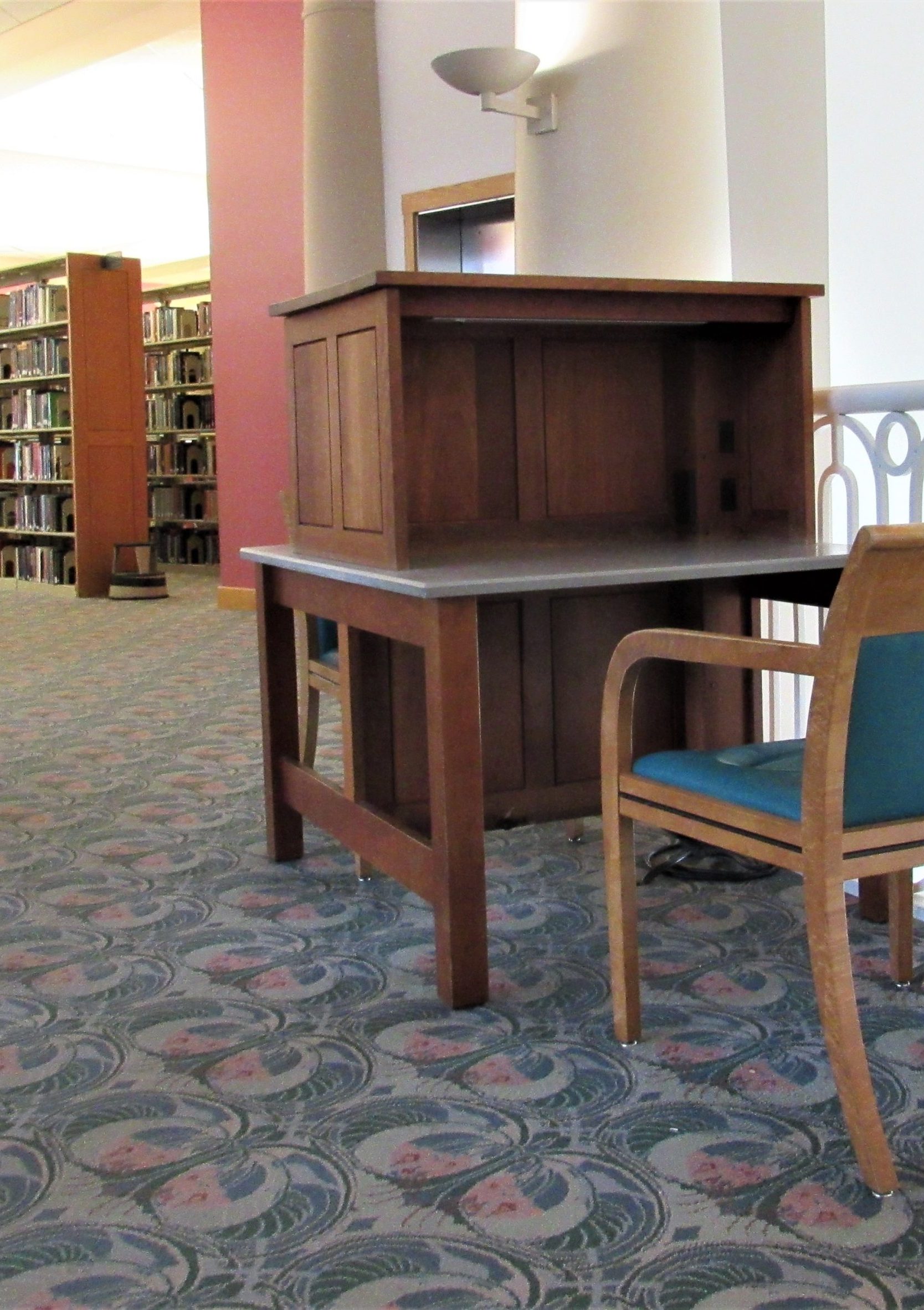 Quiet library study space on the third floor of Grainger Library featuring a wooden desk and cushioned chair near a railing and bookshelves on a carpeted floor