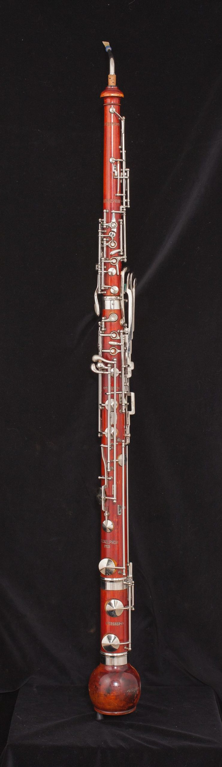 Image of a heckelphone. Double-reed instrument made of a reddish wood with metal keys.