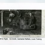 Three miners sit on a coal cart
