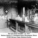 Ike and Lue Anna Brown Sanders stand behind a bar counter.