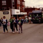 Folks in green clothing walk in front of the the Quincy Public Library bookmobile during a pre-1991 St. Patrick's Day parade
