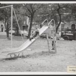 Black and white photo of two children playing on a playground slide