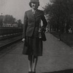Black and white photograph of Louise Huck in full World War II-era uniform on the platform next to train tracks at the Chicago & North Western depot
