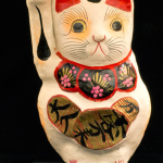 Cat figure, painted white and red. Called 'Maneki-Neko' in Japanese. Used to set in store window to invite customers in and bring good luck