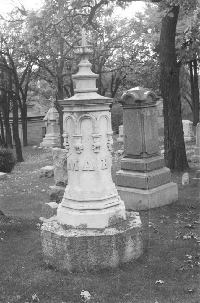 black and white photo of tombstone carved as pillar with the letters M A B visible
