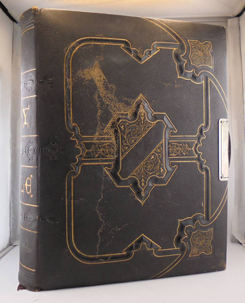 color image of a side view of a Bible with black covers and gilded engraving