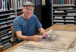 Thomas J. Bassett studying a map of the northwest coast of Africa in the Map Library's Reading Room.