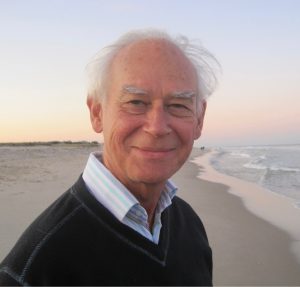 Photograph of a man (Roger Hellyer) standing on a beach.