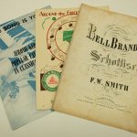 Three pieces of historical sheet music with decorative covers.