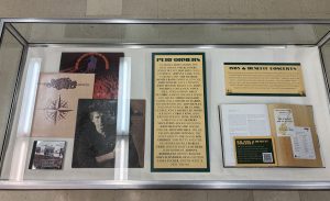 Flat exhibit case with records by Farm Aid 1085 artists, a CD recording of the show, a full list of performers, a book open to information about BB King and benefit concerts, and a caption card about 1985 and other benefit concerts like Live Aid. 