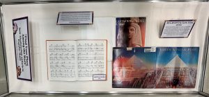 Flat exhibit case with an Earth Wind & Fire record, an Earth Wind & Fire score displaying its cover, an Earth Wind & Fire score open to the song Fantasy, and caption cards with information about Earth Wind & Fire and afrofuturism.