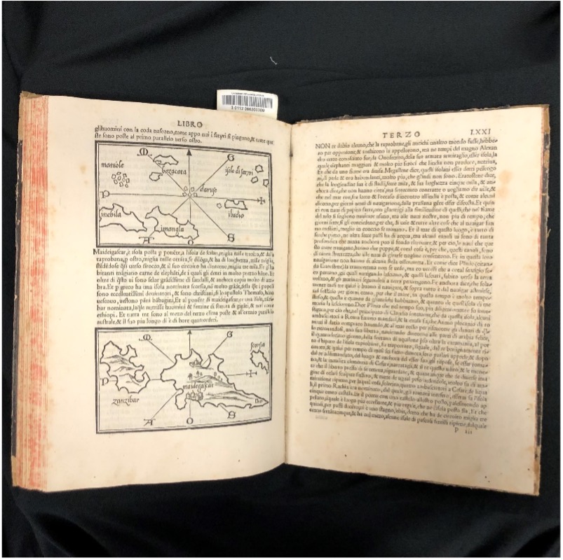 Book open to pages of text and two maps of African islands.